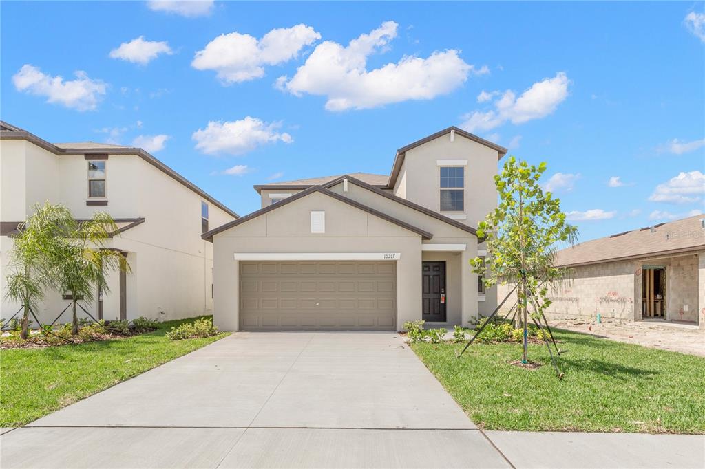 A two-story suburban house with a beige stucco exterior and a two-car garage — 10217 SUMMER KISS AVENUE, RIVERVIEW, FL