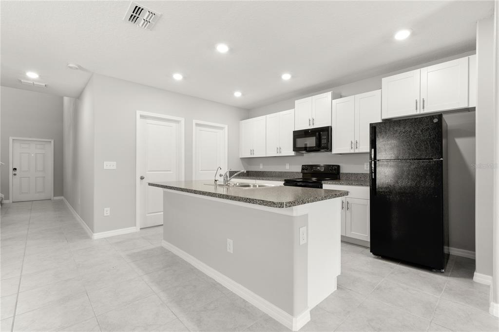 A kitchen with white cabinets, granite countertops, a kitchen island, and black appliances — 10217 SUMMER KISS AVENUE, RIVERVIEW, FL