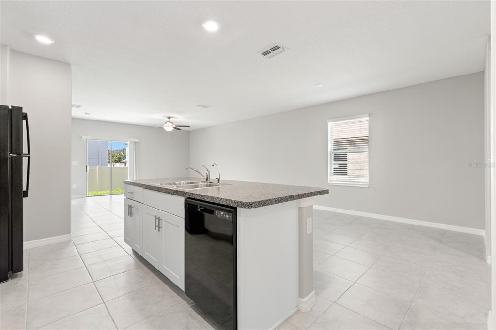 A kitchen island with a sink and dishwasher sits in a room with light tile floors — 10217 SUMMER KISS AVENUE, RIVERVIEW, FL
