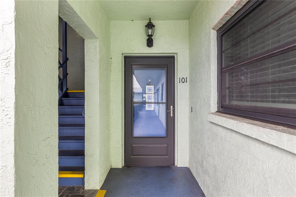 The exterior entrance of a ground-floor unit features a brown storm door labeled 101 — 5973 TERRACE PARK DRIVE N UNIT 101, ST PETERSBURG, FL