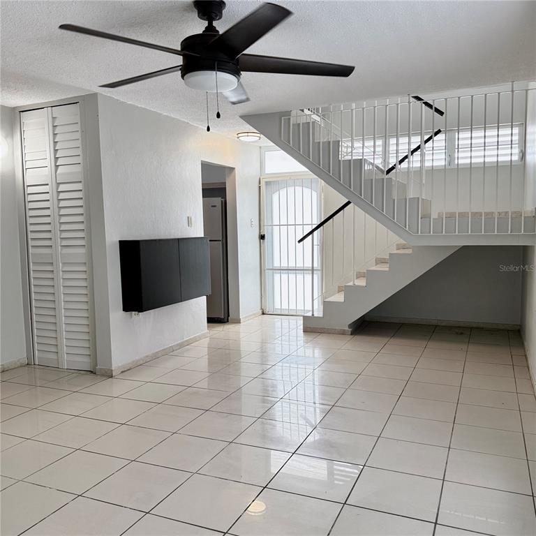 A living area features white tile floors, a ceiling fan, and a staircase with railings — 143 JARDINES DE COUNTRY CLUB UNIT CG26, CAROLINA, PR