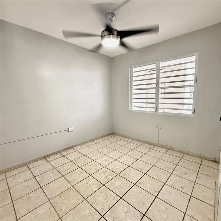 An empty room features light-colored tile flooring, gray walls, and a ceiling fan — 143 JARDINES DE COUNTRY CLUB UNIT CG26, CAROLINA, PR