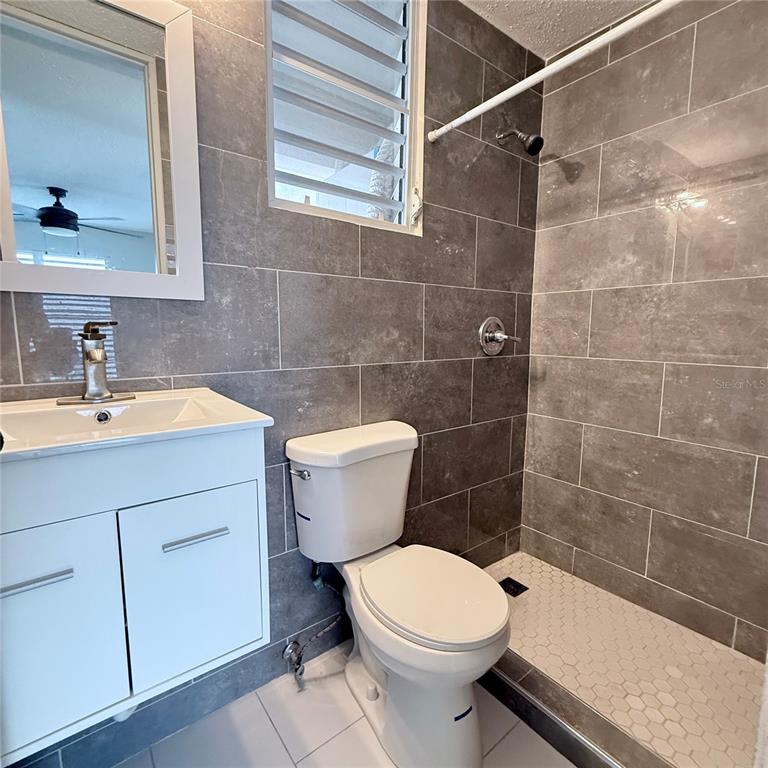 A bathroom features a white vanity, a toilet, and a walk-in shower with gray tiles — 143 JARDINES DE COUNTRY CLUB UNIT CG26, CAROLINA, PR