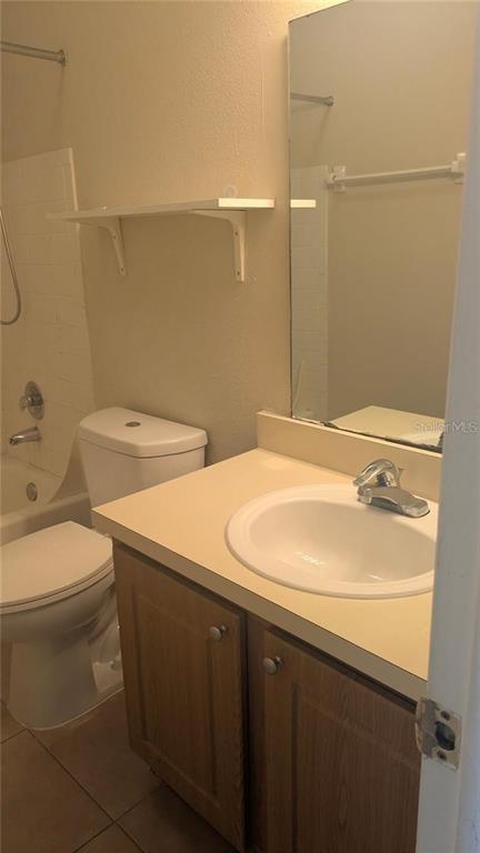 A bathroom features a white toilet, a vanity with a sink, and a wall-mounted shelf — 4113 S SEMORAN BOULEVARD UNIT 11, ORLANDO, FL