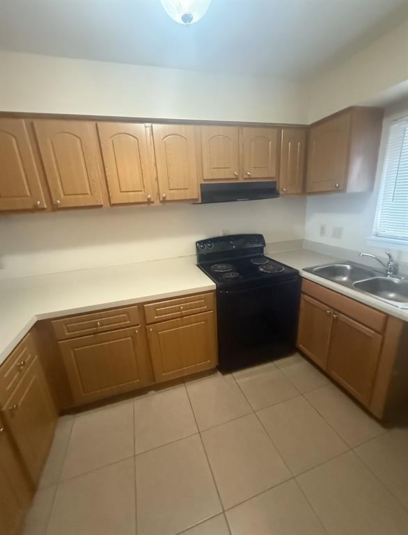 A kitchen features light wood cabinets, white countertops, a black stove, and tiled flooring — 4113 S SEMORAN BOULEVARD UNIT 11, ORLANDO, FL