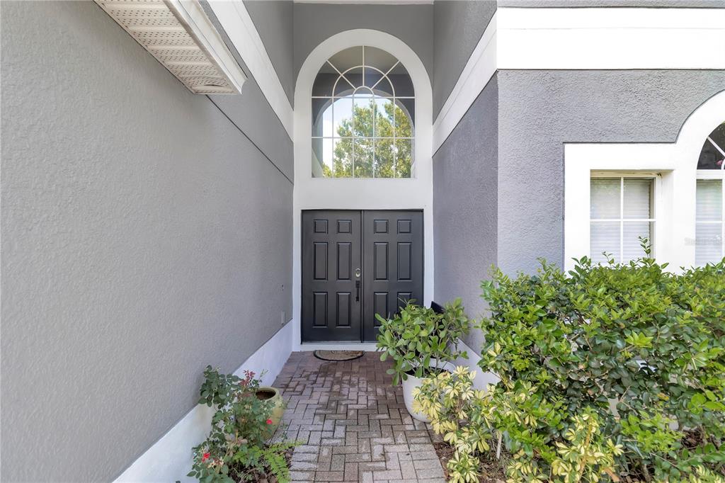 A gray house exterior features a brick walkway leading to double black front doors — 13051 MOSS PARK RIDGE DRIVE, ORLANDO, FL