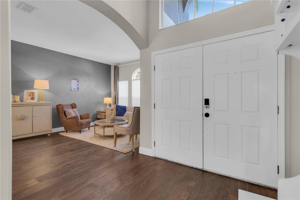 A foyer with wood-look flooring leads into a living area with an arched entryway — 13051 MOSS PARK RIDGE DRIVE, ORLANDO, FL