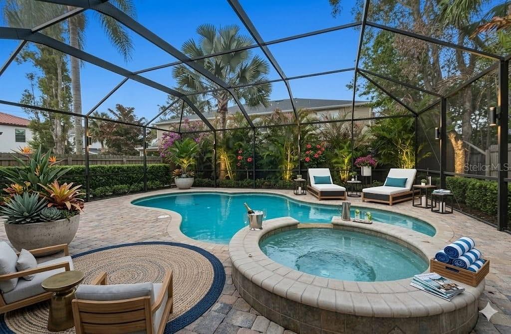 A screened-in patio features a swimming pool, a raised hot tub, and lounge chairs — 407 S TAMPANIA AVENUE, TAMPA, FL