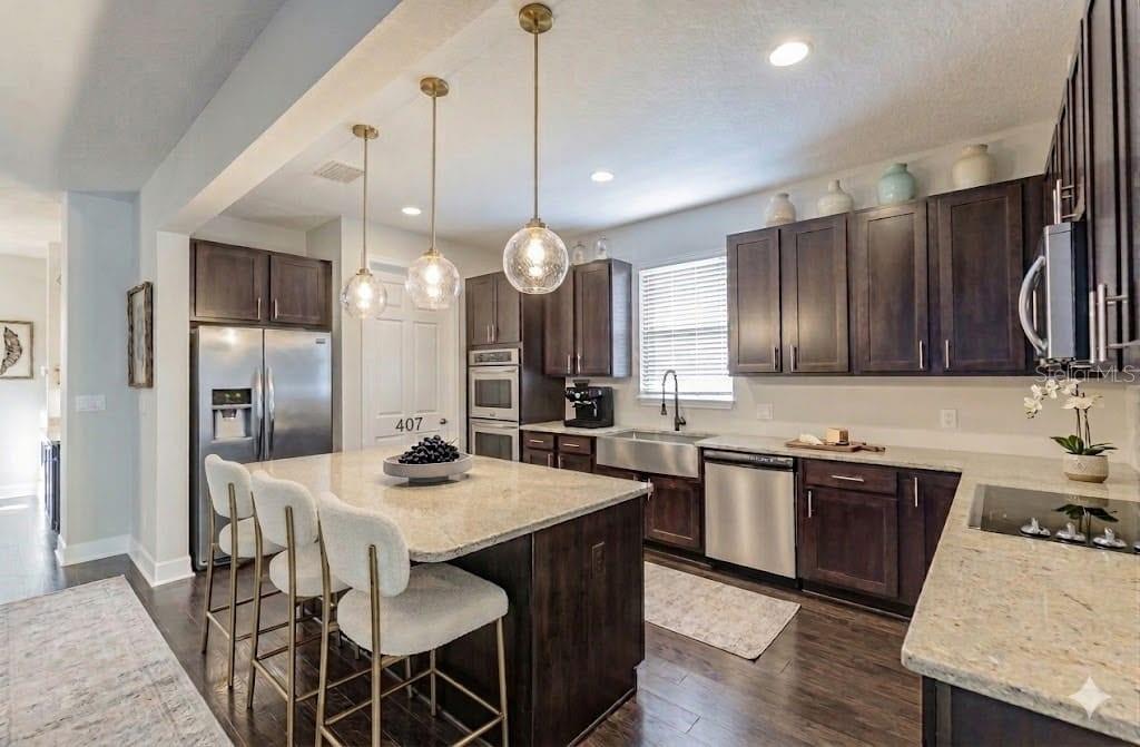 A kitchen with dark wood cabinets, granite countertops, a center island, and stainless steel appliances — 407 S TAMPANIA AVENUE, TAMPA, FL