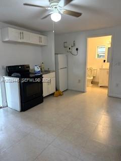 A kitchen with white cabinets, a black stove, a refrigerator, and a tiled floor — 7640 NE 3rd Pl, Miami FL 33138, MIAMI, FL
