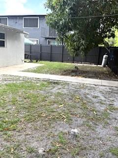 A backyard features a concrete walkway, a patch of grass, and a dark privacy fence — 7640 NE 3rd Pl, Miami FL 33138, MIAMI, FL