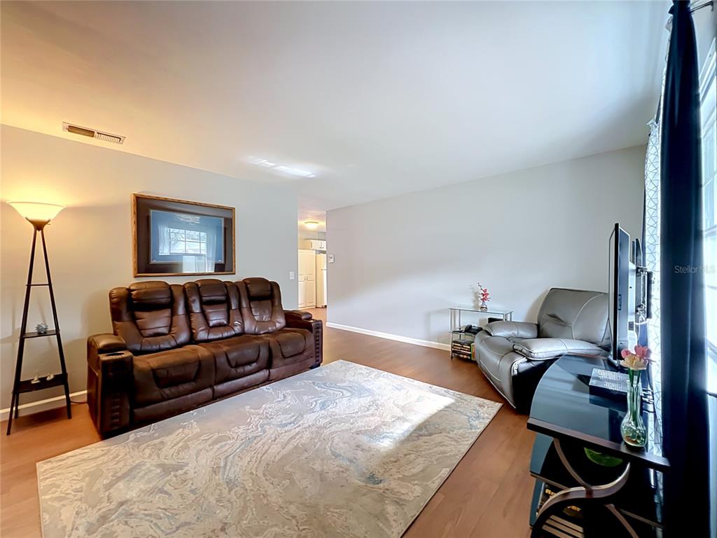 A living room features a brown leather sofa, a gray armchair, and a patterned rug — 7514 RIVERSIDE PLACE, ORLANDO, FL