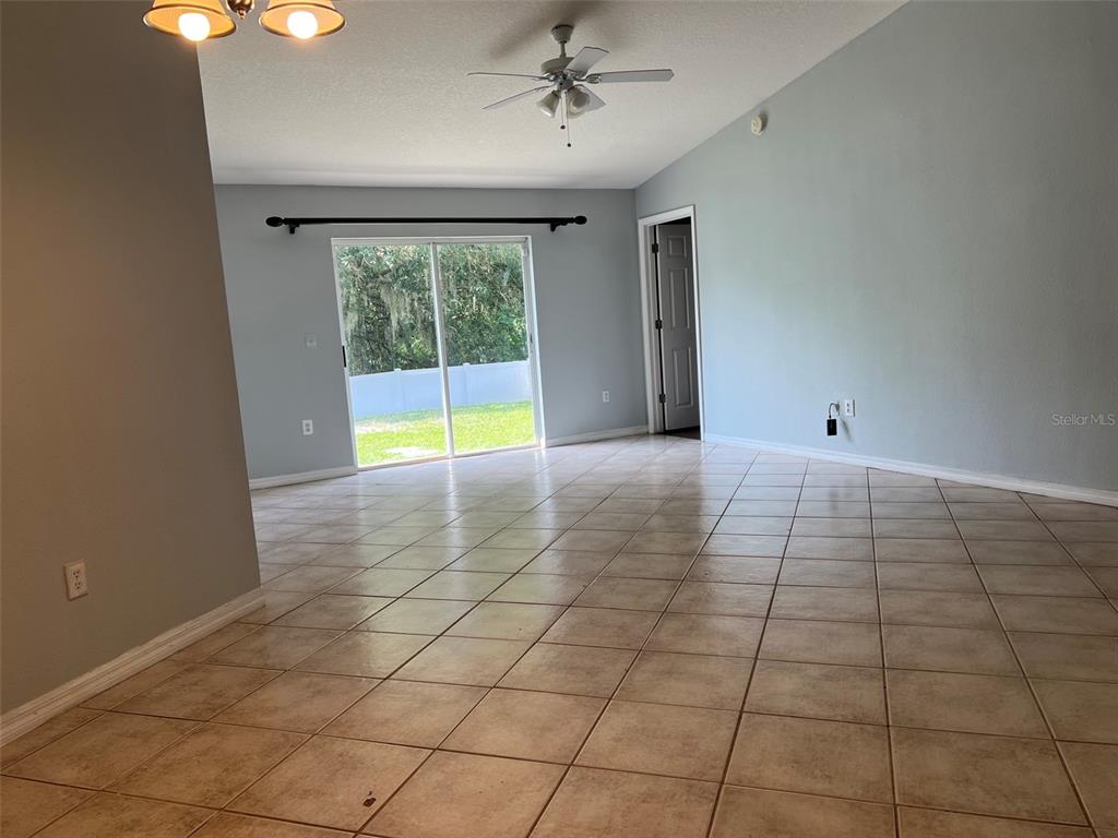 A living area with light blue walls, tile flooring, a ceiling fan, and sliding glass doors — 18169 SANDY POINTE DRIVE, TAMPA, FL