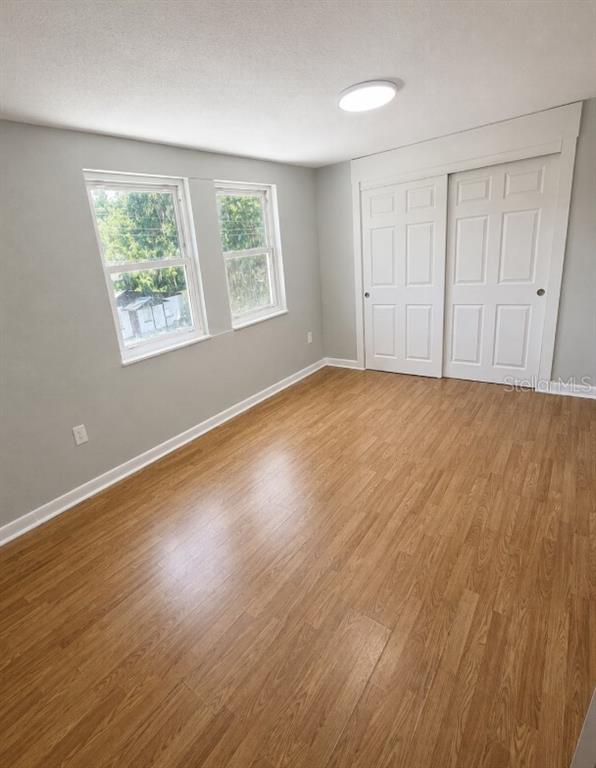 A bedroom features light gray walls, wood-look flooring, two windows, and a white sliding closet — 837 LAFAYETTE LANE, LAKELAND, FL