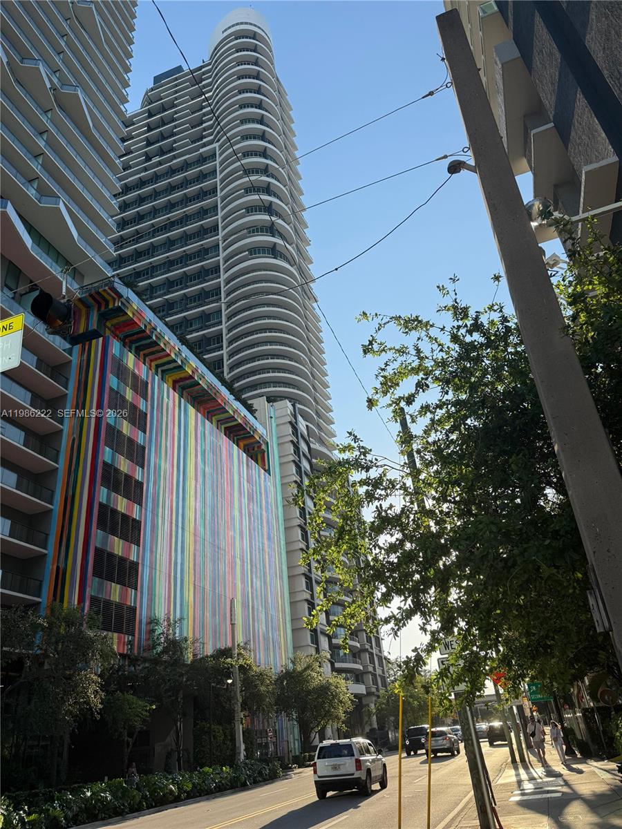 A tall, curved residential tower stands next to a parking garage with a colorful facade — 60 SW 13th St # 3017, Miami FL 33130, MIAMI, FL
