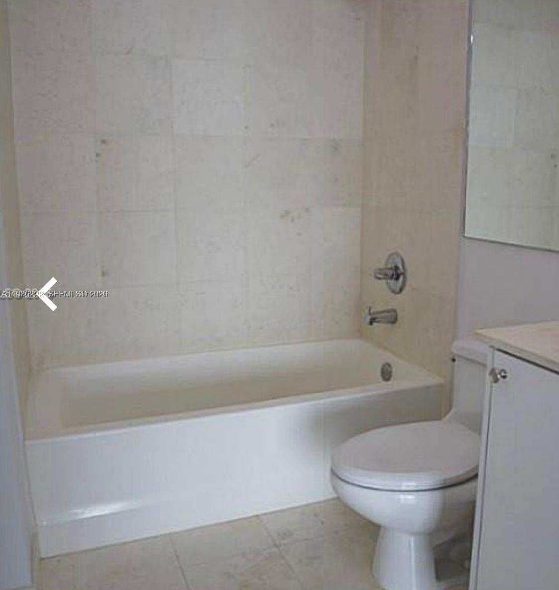 A bathroom features a white bathtub, a toilet, and light-colored tiled walls — 60 SW 13th St # 3017, Miami FL 33130, MIAMI, FL