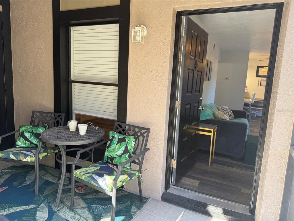A patio with a small table and two chairs sits outside an open front door — 4025 ANGEL OAK COURT UNIT 103, TAMPA, FL