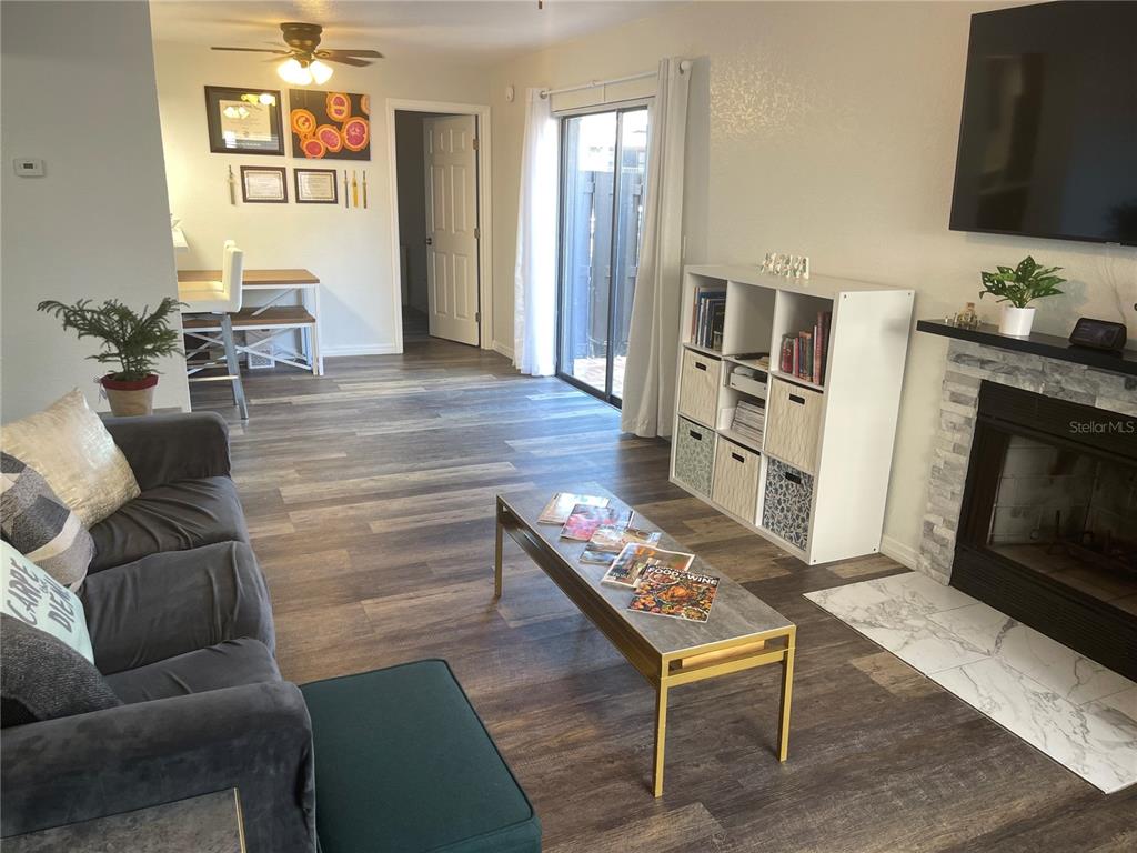 A living room features wood-look flooring, a fireplace, a white shelving unit, and a sofa — 4025 ANGEL OAK COURT UNIT 103, TAMPA, FL