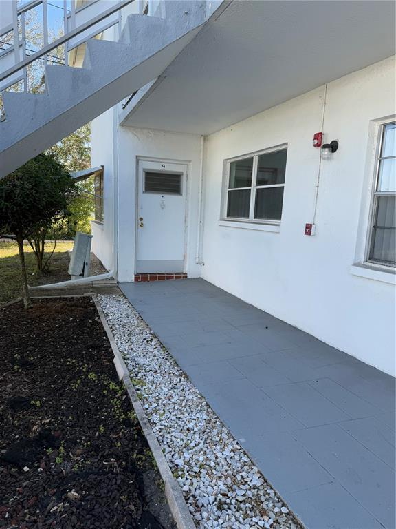 A white apartment building exterior features a gray painted walkway, a numbered door, and stairs — 5895 18TH STREET N UNIT 9, ST PETERSBURG, FL