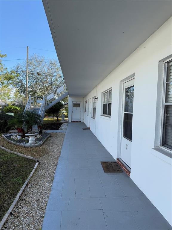 An exterior view of a building with a covered walkway, white walls, and metal stairs — 5895 18TH STREET N UNIT 9, ST PETERSBURG, FL