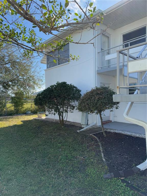A two-story white building exterior features a metal staircase, windows, and two small trees — 5895 18TH STREET N UNIT 9, ST PETERSBURG, FL