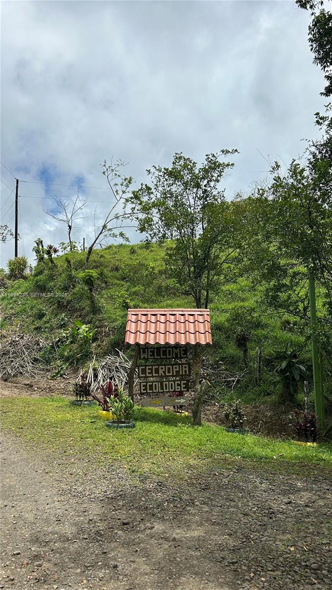 A sign with a tiled roof welcomes visitors to Cecropia Ecolodge on a dirt road — Distrito 14 San Lorenzo, FL A-0190479, FL
