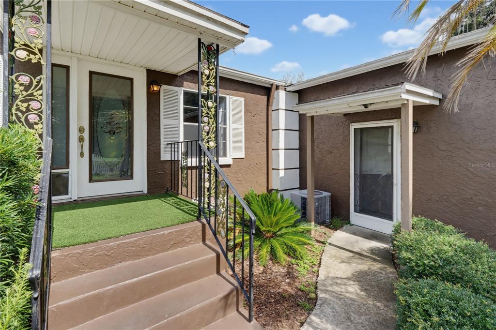 An exterior view of a brown house with a front porch, steps, and two doors — 7421 HENRY DRIVE, LAND O LAKES, FL