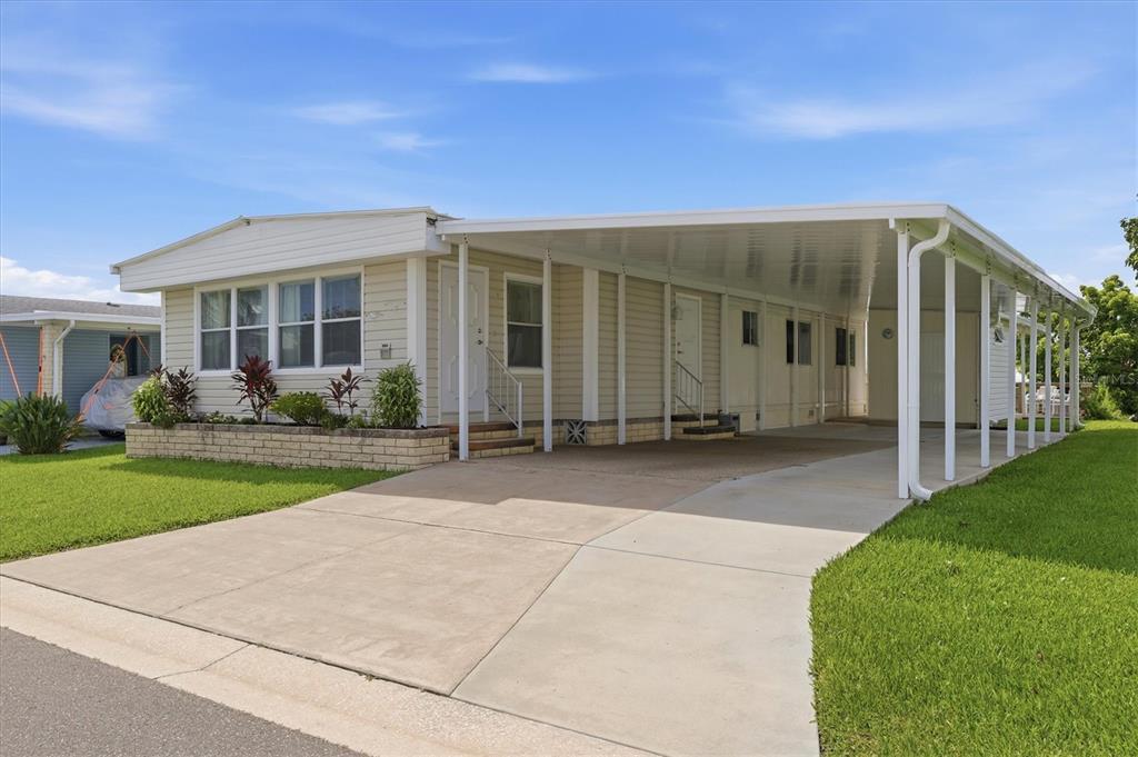 A single-story manufactured home with a large attached carport and a concrete driveway — 4323 13TH STREET E, ELLENTON, FL