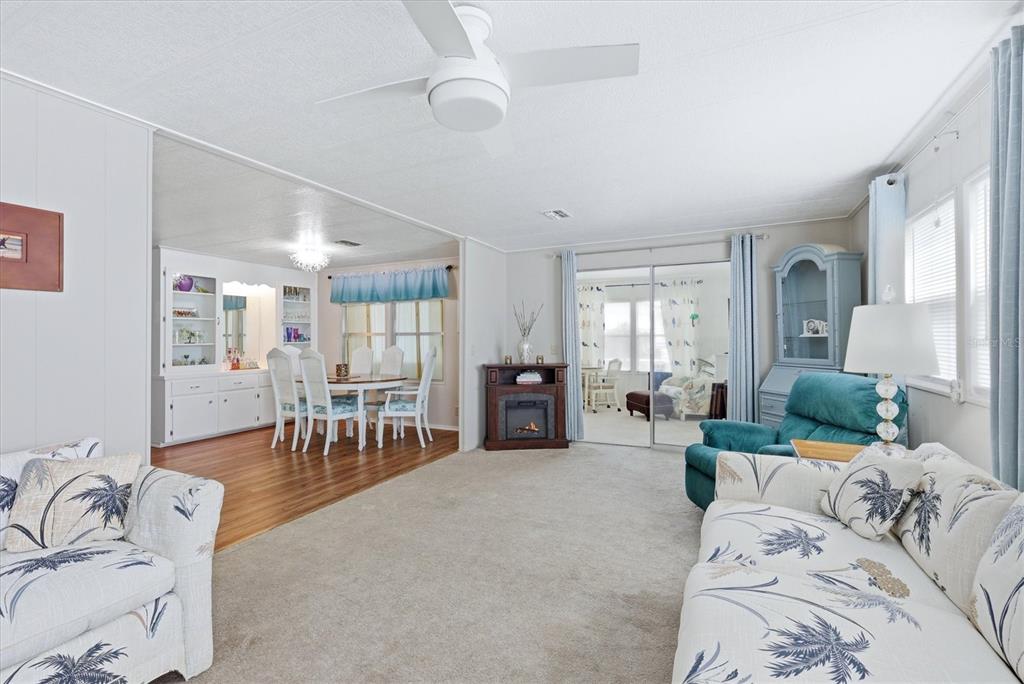 A living room with carpet, a ceiling fan, and an adjacent dining area with wood flooring — 4323 13TH STREET E, ELLENTON, FL
