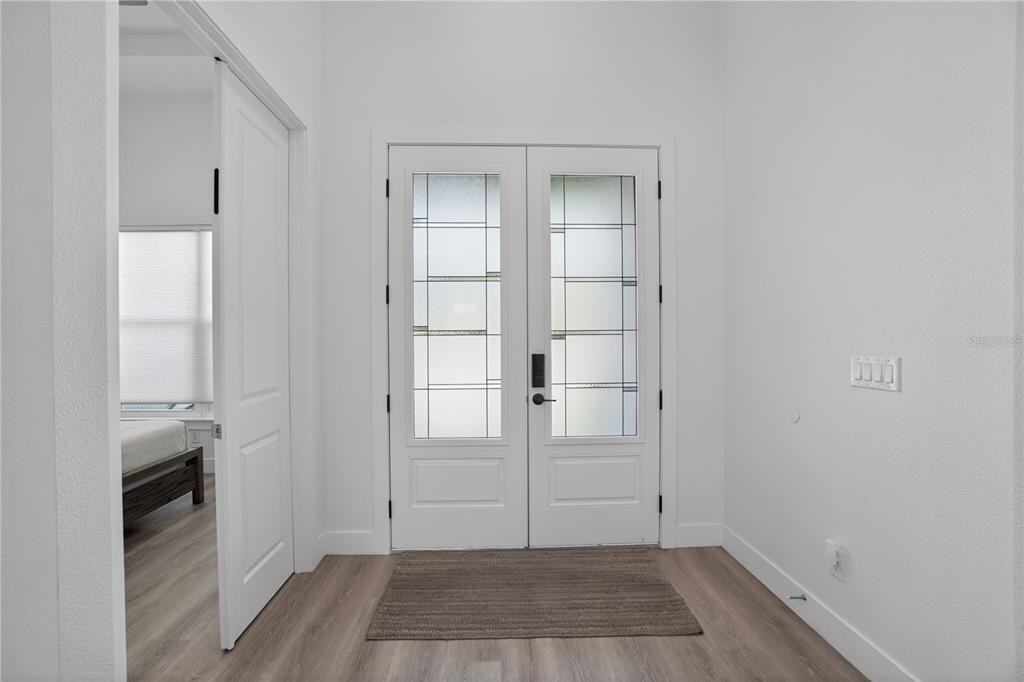 A bright entryway features white double doors with glass panels, light wood floors, and white walls — 3090 QUARTER STREET, NORTH PORT, FL
