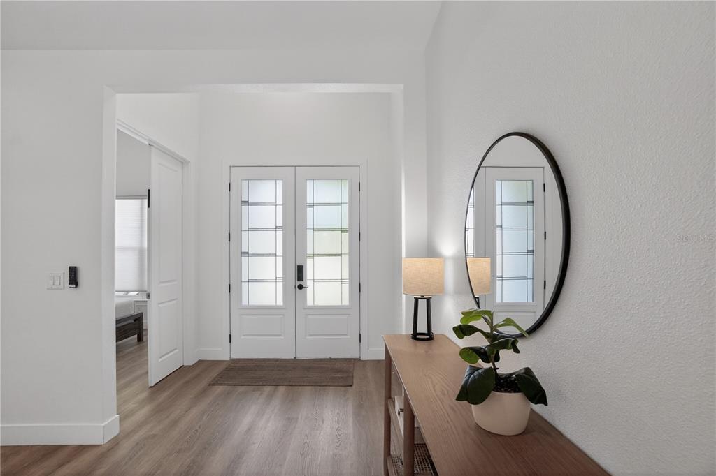 An entryway features white walls, light wood-look flooring, a console table, and double front doors — 3090 QUARTER STREET, NORTH PORT, FL