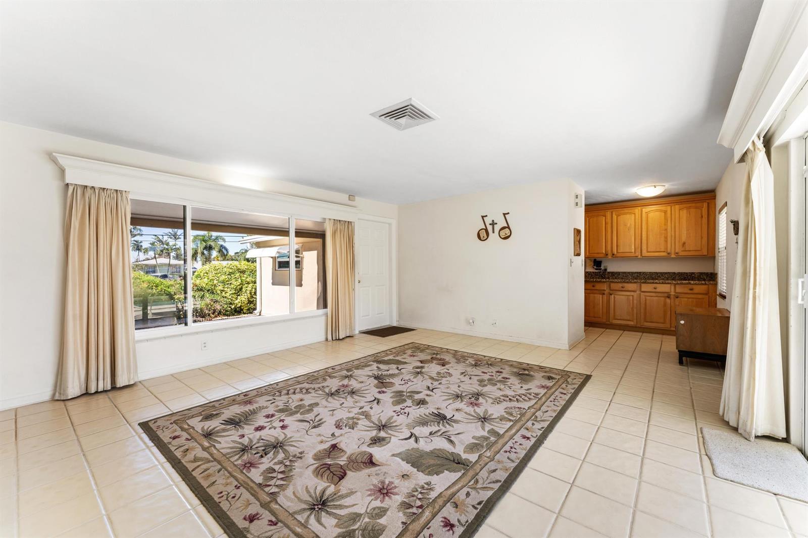A living room with tile floors, a large window, and an adjacent kitchen area — 1812 High Ridge Road, Lake Worth FL 33461, LAKE WORTH, FL