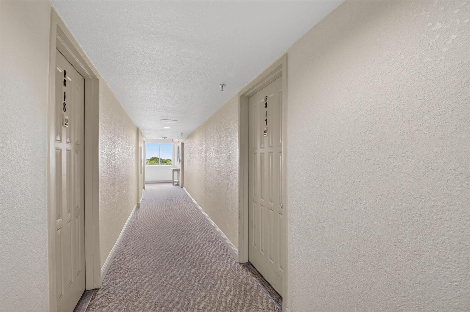 A carpeted apartment hallway features two doors with unit numbers and a window at the end — 5280 NW 2nd Ave # 17, Boca Raton FL 33487, BOCA RATON, FL