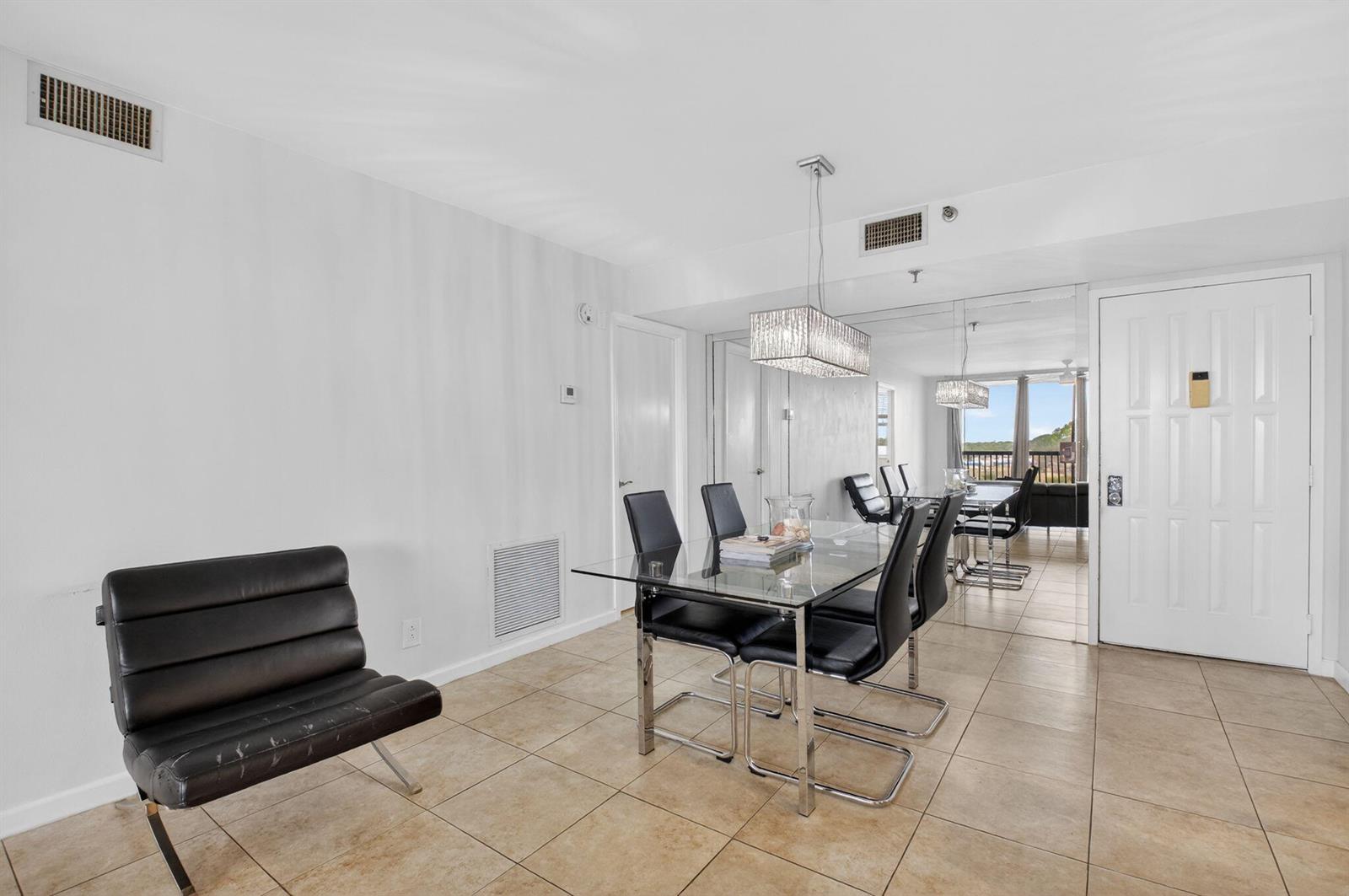 A dining area features a glass table, black chairs, tile flooring, and a mirrored wall — 5280 NW 2nd Ave # 17, Boca Raton FL 33487, BOCA RATON, FL