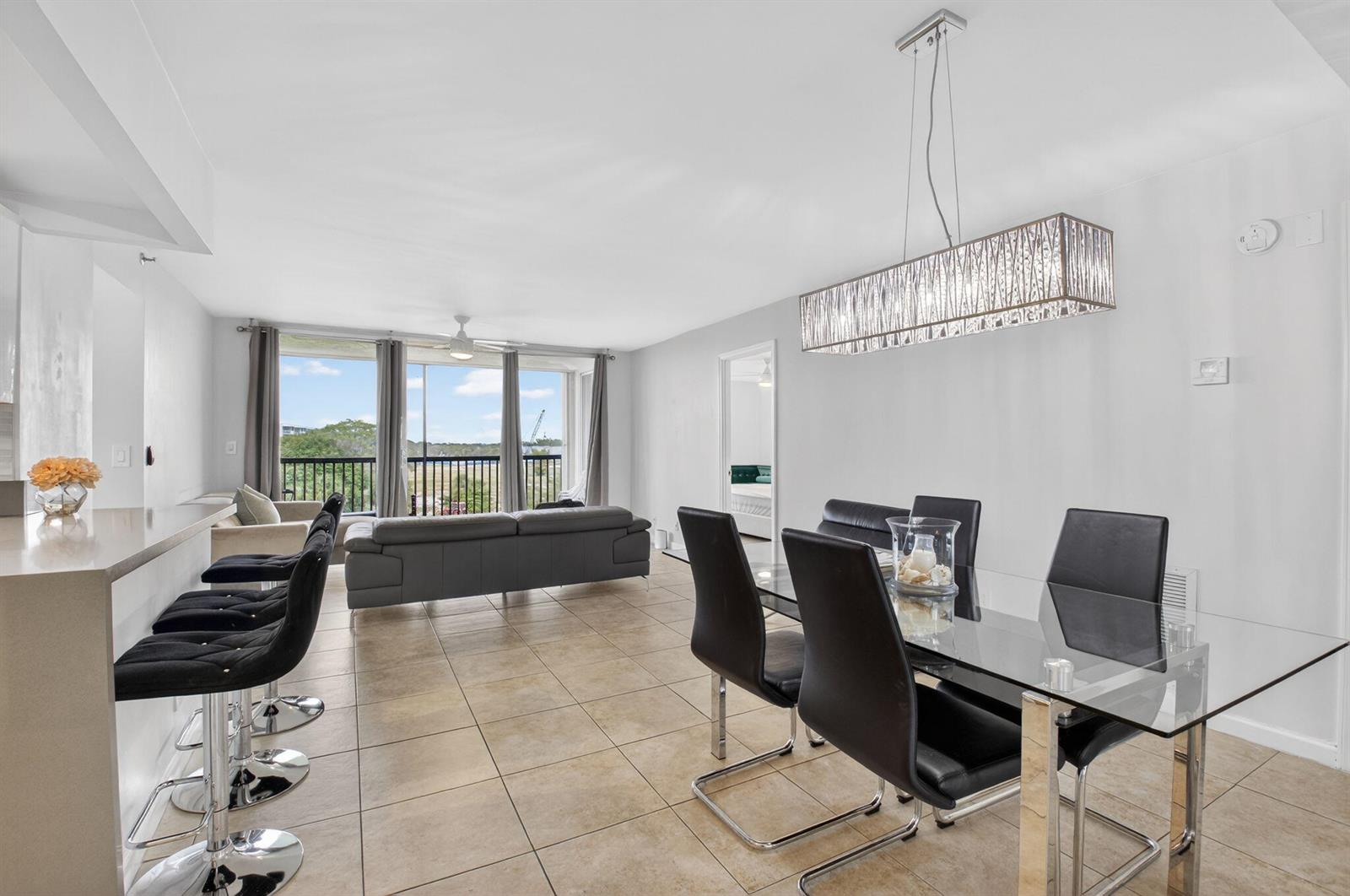 A dining area with a glass table and a living room with a balcony view — 5280 NW 2nd Ave # 17, Boca Raton FL 33487, BOCA RATON, FL