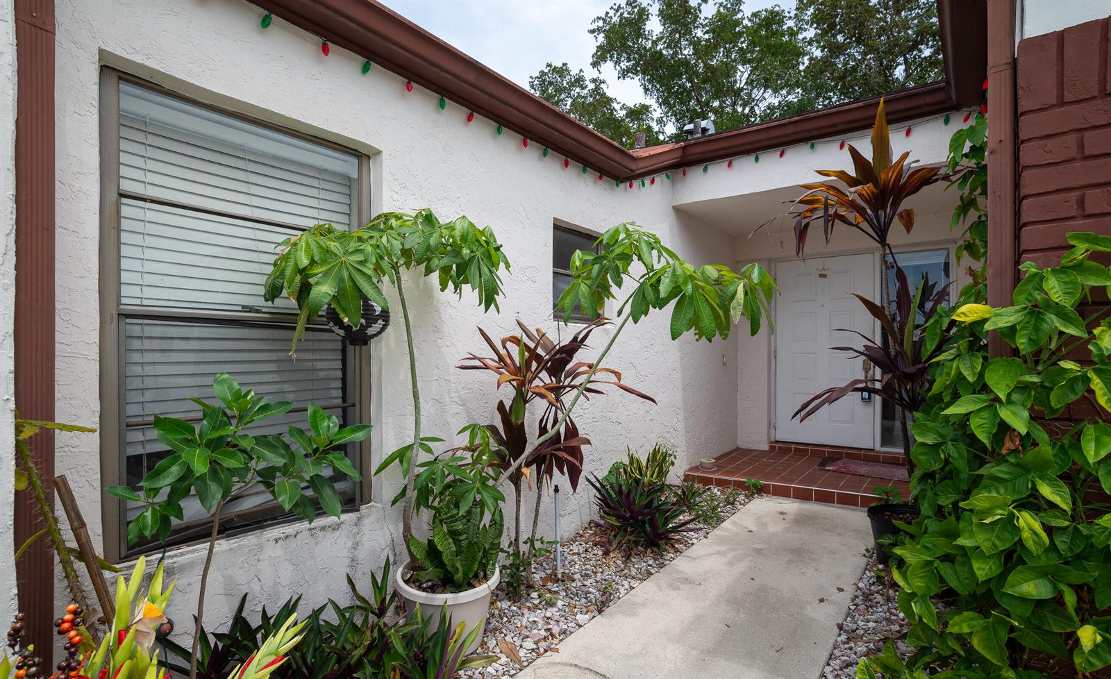 A white stucco house exterior features a front walkway, potted plants, and a white door — 11690 Timberwood Road, Boca Raton FL 33428, BOCA RATON, FL