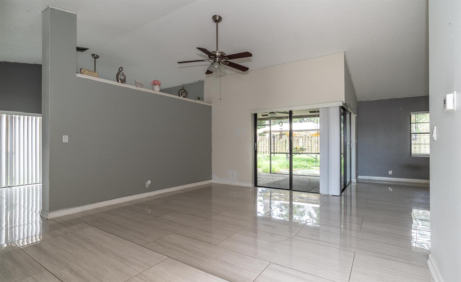 An open living area features gray walls, light-colored tile flooring, a ceiling fan, and sliding doors — 11690 Timberwood Road, Boca Raton FL 33428, BOCA RATON, FL