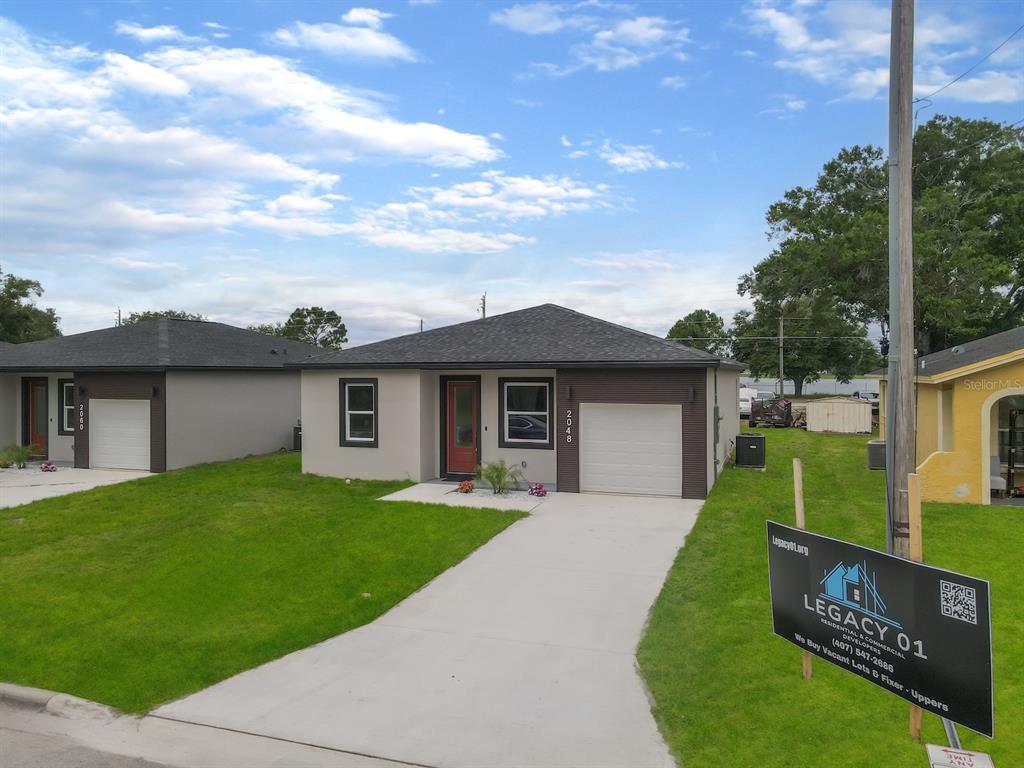 A modern, single-story house with a concrete driveway and a prominent real estate sign — 2048 DIXIE AVENUE, SANFORD, FL