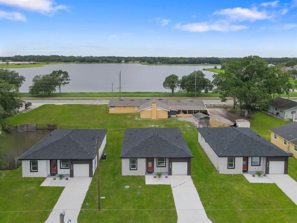 An aerial view shows three modern houses in the foreground facing a lake across a road — 2048 DIXIE AVENUE, SANFORD, FL