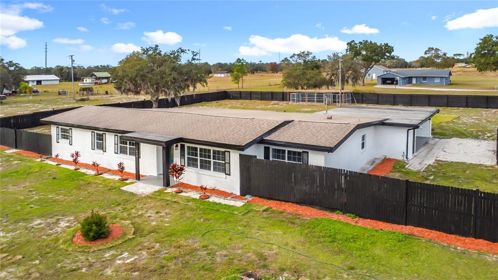 An aerial view of a white, single-story house with a dark roof and fenced yard — 1890 TYNER ROAD, HAINES CITY, FL