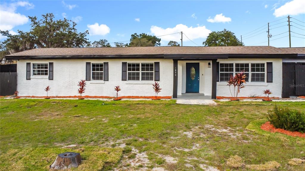 A single-story white brick house with a blue front door and black shutters — 1890 TYNER ROAD, HAINES CITY, FL