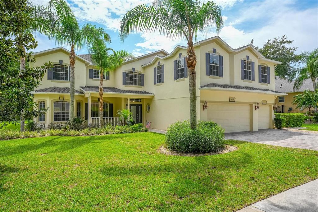 A two-story suburban house with a three-car garage, palm trees, and a manicured lawn — 6054 TREMAYNE DRIVE, MOUNT DORA, FL