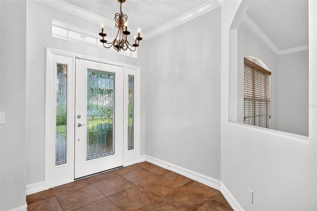 An entryway features a white front door with glass panels, tile flooring, and a chandelier — 6054 TREMAYNE DRIVE, MOUNT DORA, FL
