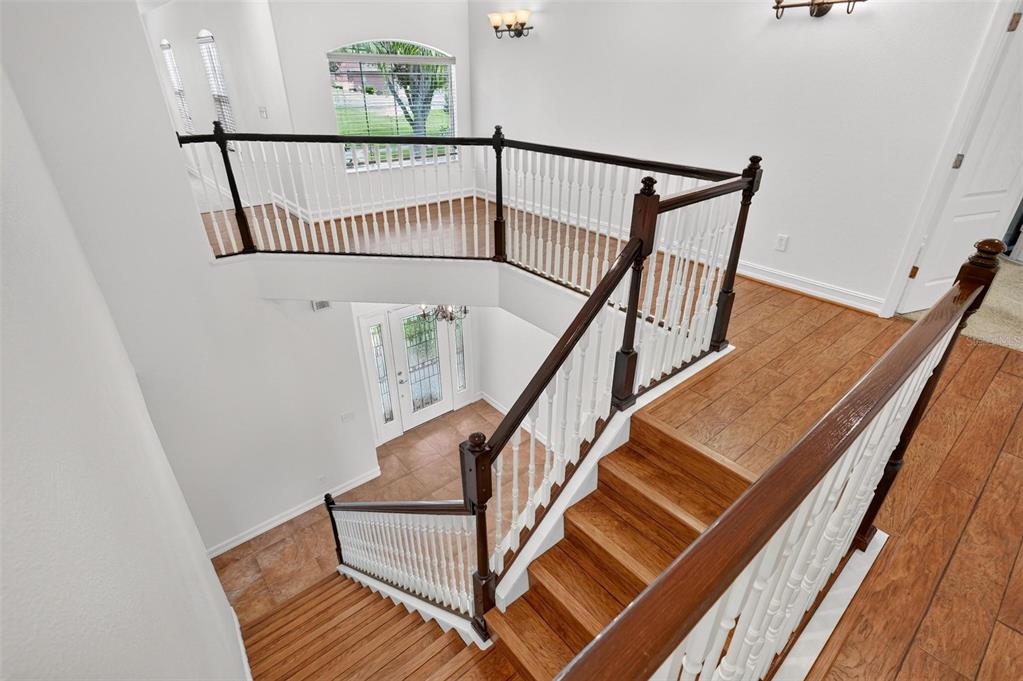 A high-angle view of a wooden staircase with white railings overlooking a tiled entryway — 6054 TREMAYNE DRIVE, MOUNT DORA, FL
