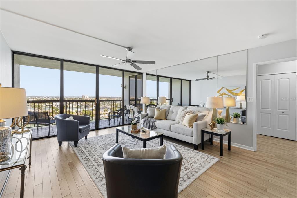 A living room features a sofa, two armchairs, a glass coffee table, and a balcony view — 9495 BLIND PASS ROAD UNIT 905, ST PETE BEACH, FL