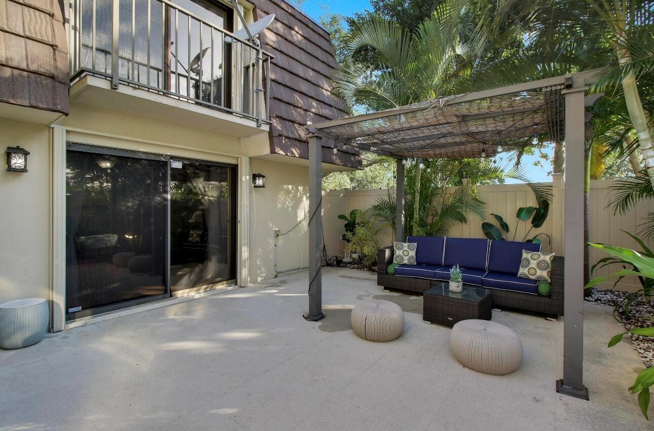 A patio features a pergola, outdoor sofa, two ottomans, and a sliding glass door — 6906 69th Way, West Palm Beach FL 33407, WEST PALM BEACH, FL