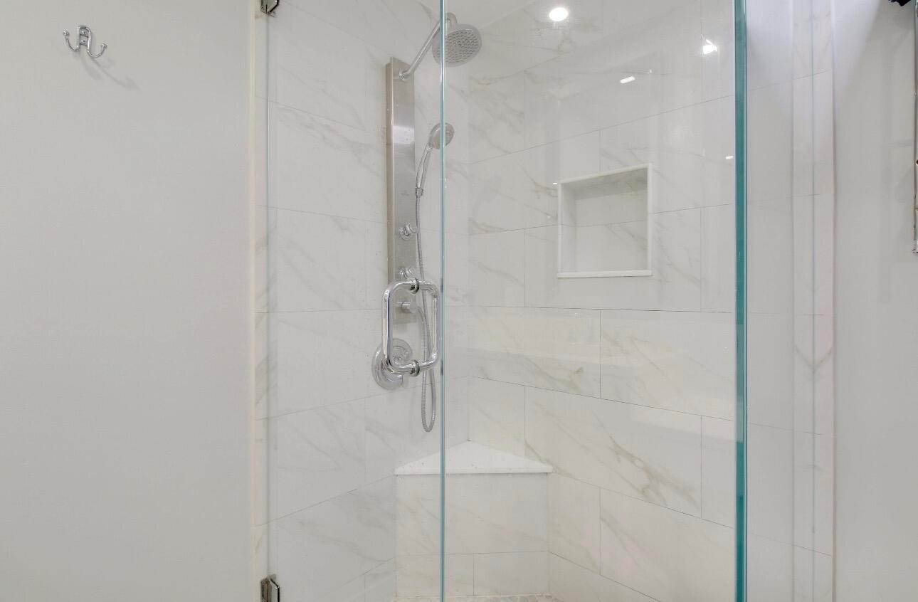 A walk-in shower with white marble-look tile, a glass door, and a built-in corner seat — 6906 69th Way, West Palm Beach FL 33407, WEST PALM BEACH, FL
