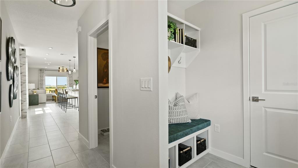 A hallway features a built-in mudroom bench with storage cubbies and a view into a kitchen — 1952 DIAMOND HEAD CIRCLE, HAINES CITY, FL