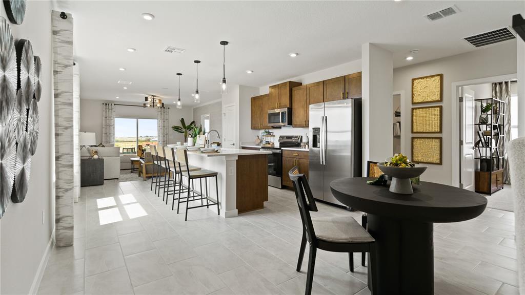 A modern kitchen with wood cabinets, stainless steel appliances, and a central island with seating — 1952 DIAMOND HEAD CIRCLE, HAINES CITY, FL