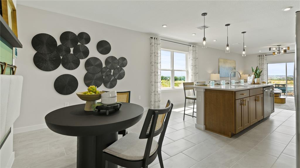 A dining area with a round table sits next to a kitchen island with stools — 1952 DIAMOND HEAD CIRCLE, HAINES CITY, FL